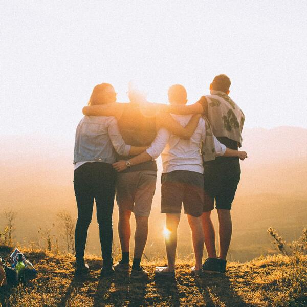 4 Jugendliche umarmen sich vor Sonnenuntergang